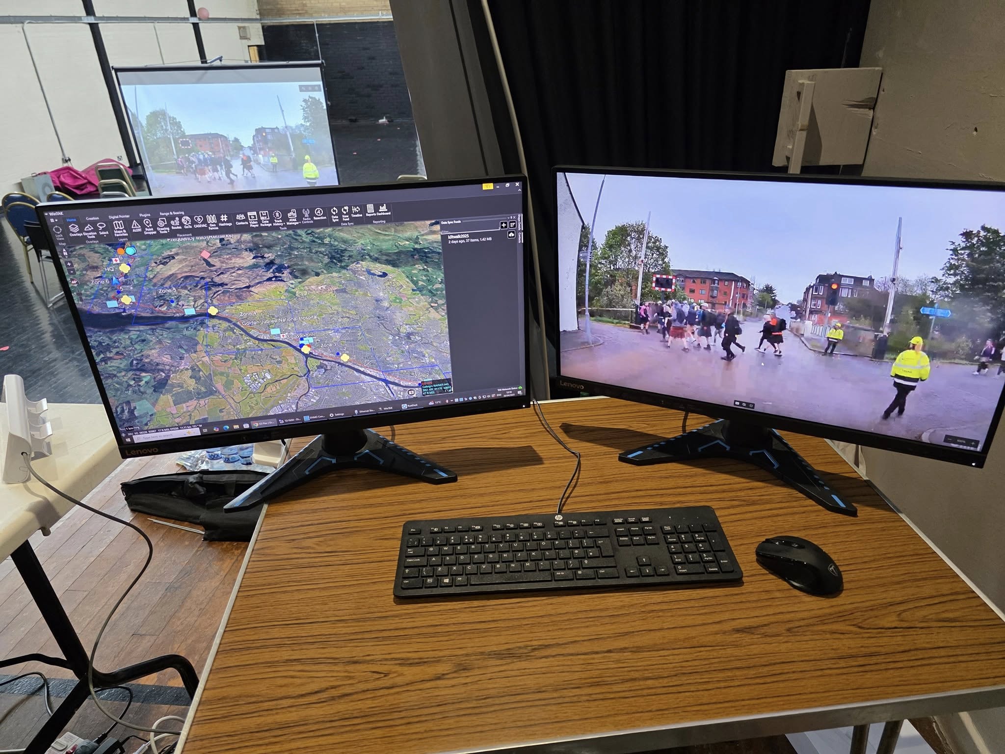 Volunteers from RAYNET in hi-vis working at the ERCS event control room desk, surrounded by radio equipment, laptops and dual operator monitors.