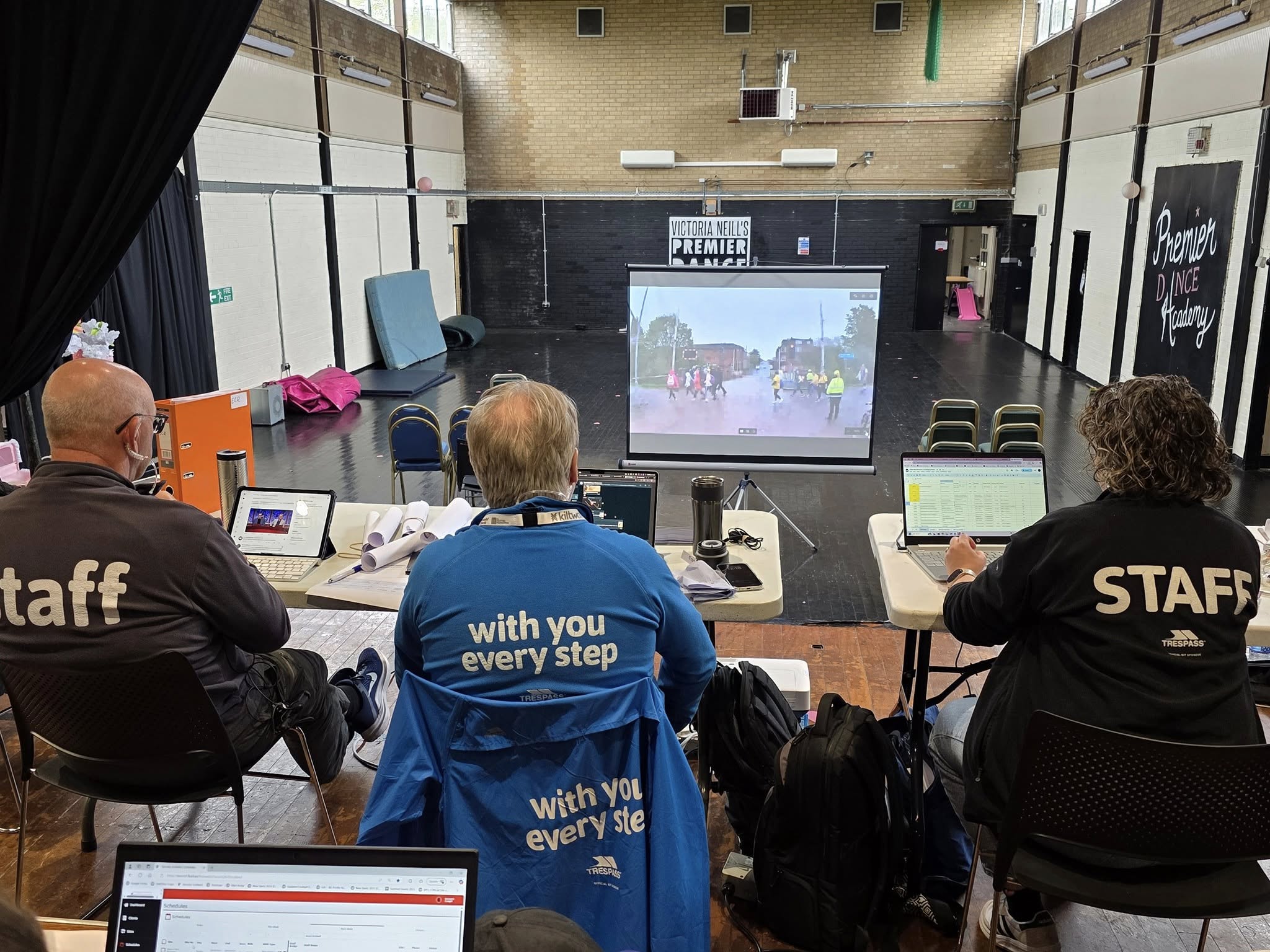 Dual screens inside an ERCS control room showing a WinTAK map view with zones and assets plotted, alongside a live camera feed of a public event.